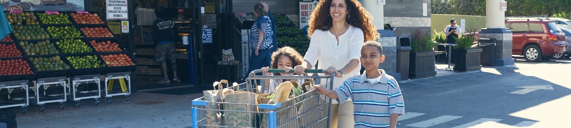 A family pushes a cart full of groceries
