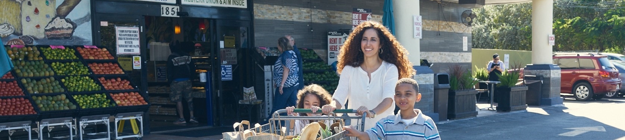 A family pushes a cart full of groceries