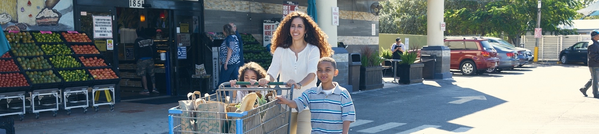 A family pushes a cart full of groceries